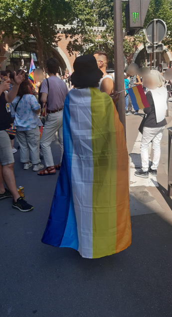 A person in a city proudly carrying the Aroace flag to show their support for the aroace and LGBTQ+ cause.